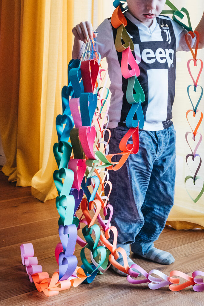 Lass uns eine Herz-Girlande aus Papierstreifen basteln.